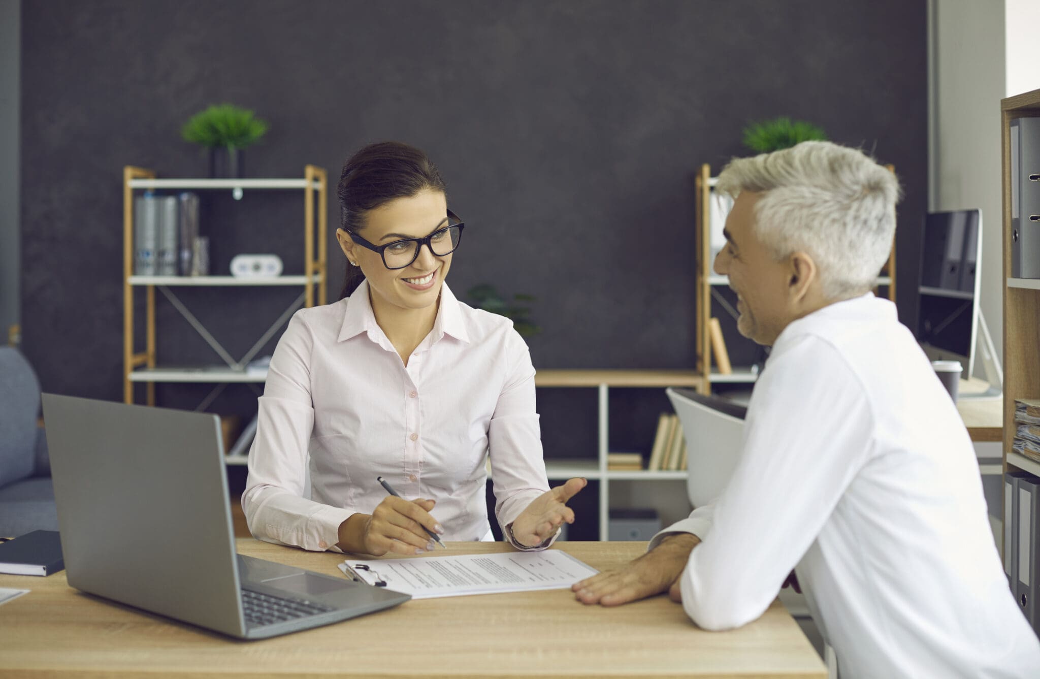 Two people discussing paperwork in office.