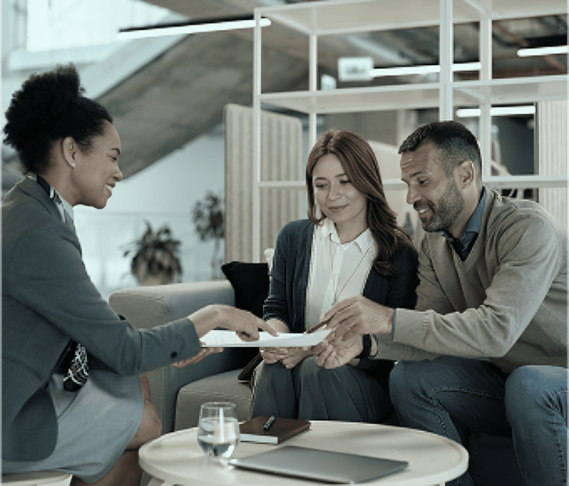 Three people discussing documents in office.