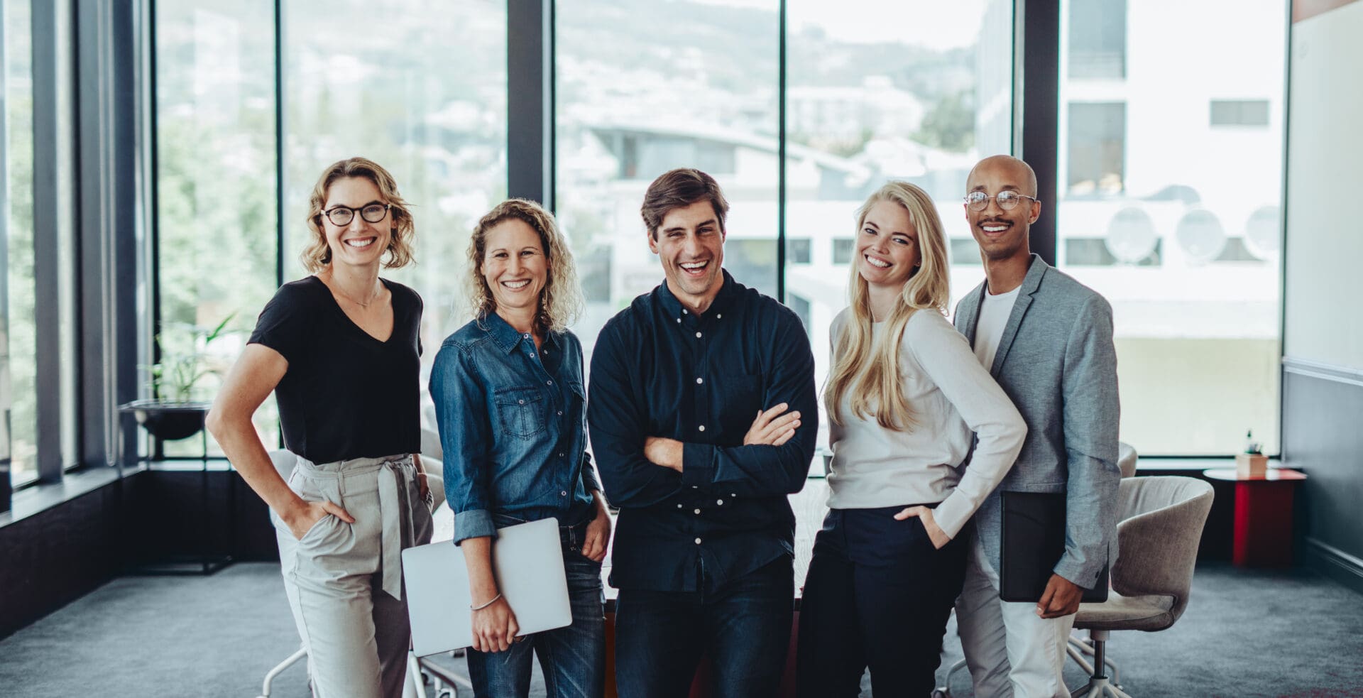 Portrait of a multi-ethnic business team smiling together in office meeting room. Group of colleagues looking at camera and laughing.