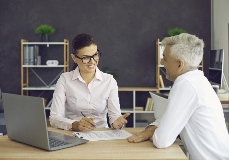 Two people discussing paperwork in office.